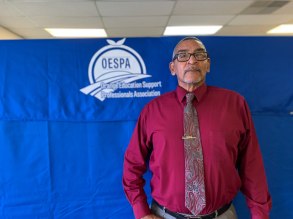 Ronald Pollard stands in front of the a blue and white OESPA banner